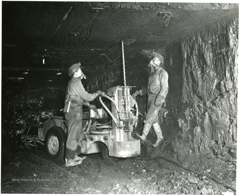 Miners using a machine to bolt the mine roof.