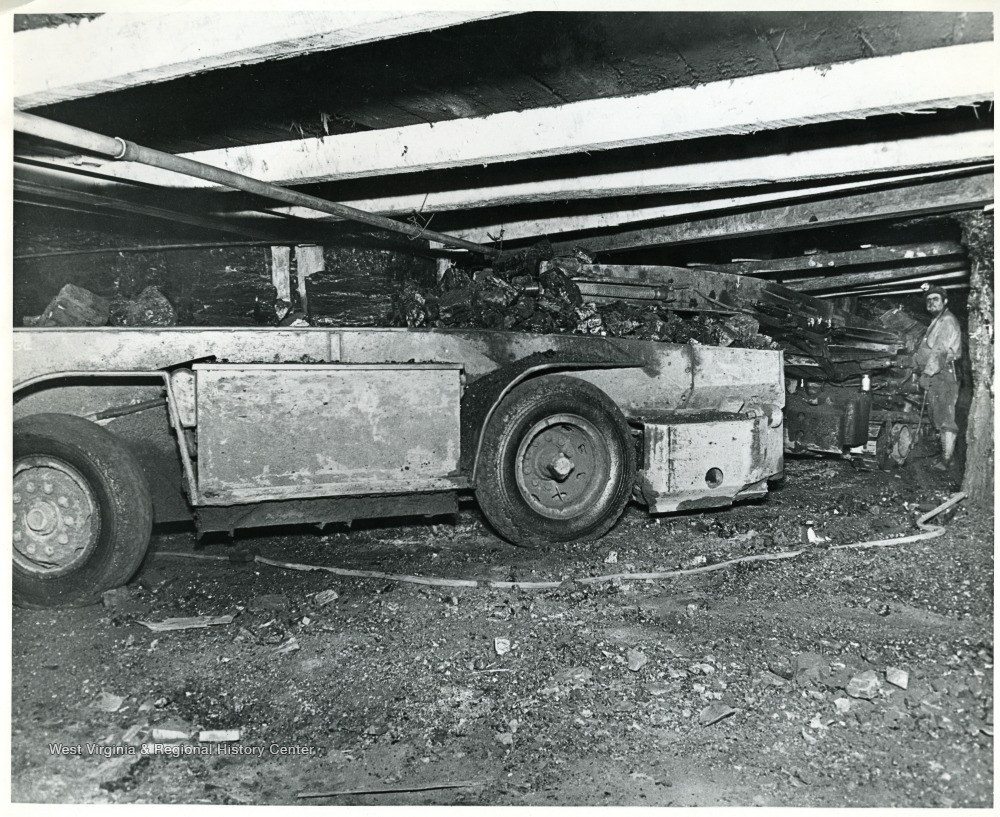 Miner watches as coal loads into a shuttle car.