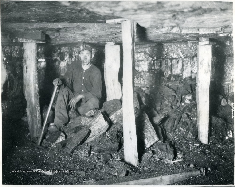'Safety first is stressed in every possible way in White Oak mines. Note the posts set to protect this man at his labor. He is waiting for another mine car so he can clean up his work place and make it ready for the mining machine crew who will cut it during the night ready for him to work tomorrow.'