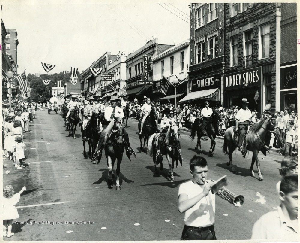People on horses ride down High Street for a parade.