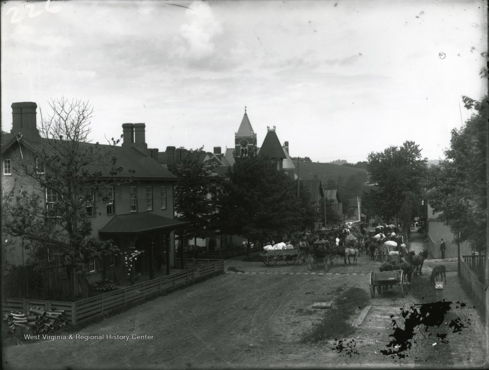 An early wool market in downtown Morgantown. Horses and buggies on the road in the center.