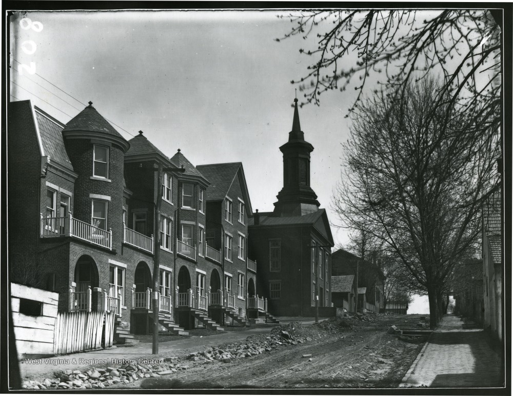 View of brick row houses and Methodist Episcopal Church 'now Cohen's Furniture' on Pleasant St before it was paved in Morgantown W. Va.