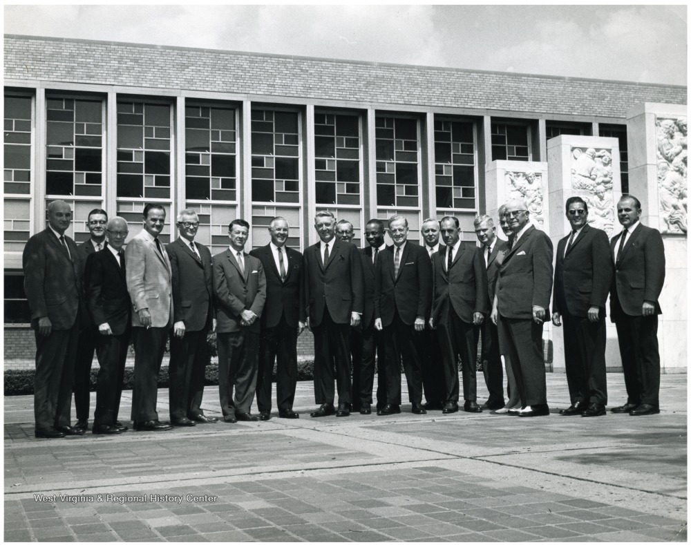 'Left to right: E.J. Nesius, Director of Application Center; Robert F. Munn, Provost and Librarian (in back); Rey Smith, State Superintendent of Schools; Don Robertson, Attorney General; Robert Baily, Secretary of State (W. Va.); Harry Heflin, Acting President of WVU; Hulett Smith, Governor; four unknown people; Denzil Gainer, State Auditor; three unknown people; William McMillion, Comptroller; Harold Shamberger, Assistant to President of University.'