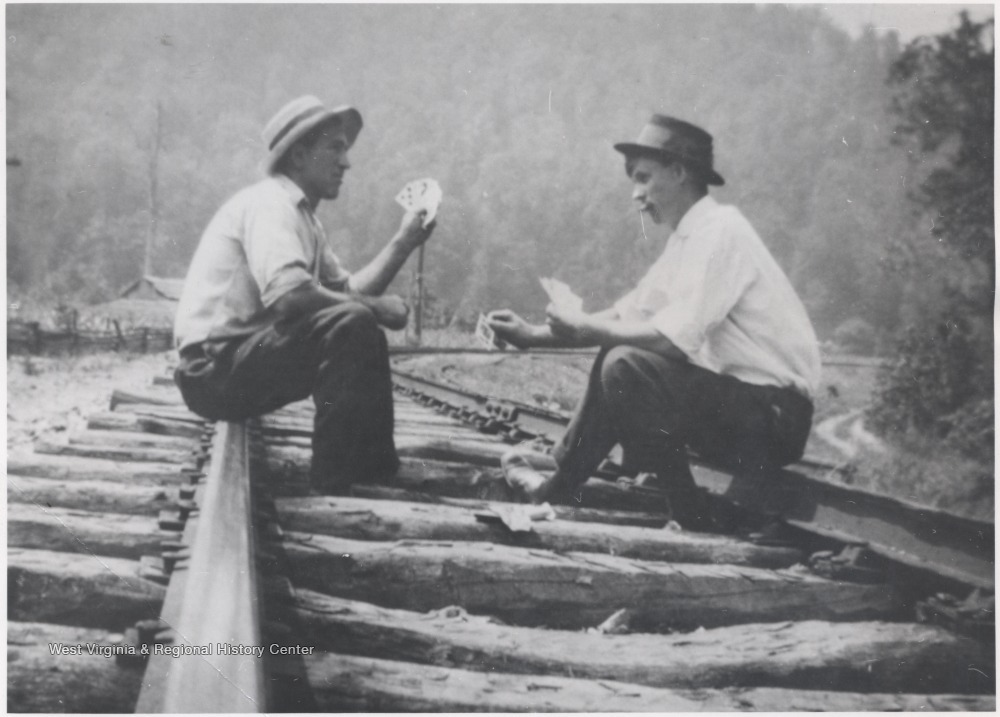 Steve and Becca Bragg pictured holding playing cards and smoking cigars on top of the tracks. 