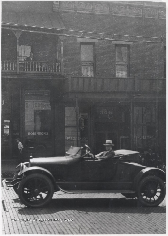 An unidentified man sits in his automobile between Ballengee and Temple Streets.