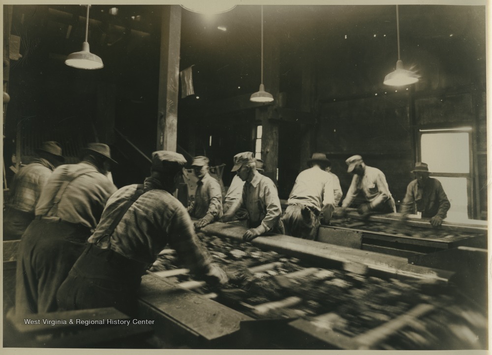 A group of coal miners sort through samples of coal. Subjects unidentified. 