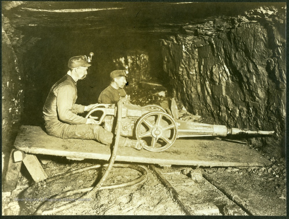 "The miner is using a compressed-air drill to drive a hole in the lower edge of the working face of the coal vein."