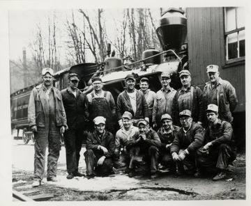 Group portrait of men standing in front of a train.  