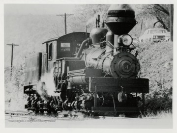 Train engine on tracks beside a hill.  