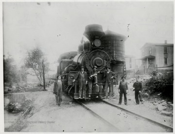 Front view of Shay No. 11 train engine at the water tank with six crew members in front.  
