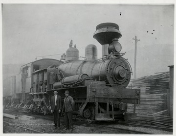 Shay No. 8 train engine with two men standing beside it and two men in the cabin.