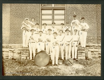 Marching band poses with several members wearing an American flag in their hair. Front row, L to R: 1. A. E. Sampson; 2. Unidentified; 3. Edd Maxwell; 4. Prof. Erwin; 5. Evert Shrewsberry; 6. J. G. Hutchinson; 7. Lawrence Spencer; 8. John Martin; 9. Walter Smith; 10. James H. McGinnis; 11. __ Mauck; 12. Lucien Davis; 13. E. O. Phlegan; 14. Charley Bailey; 15. ___ Frazier; 16. Edd Martin