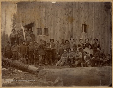 Logging crew poses in front of building.