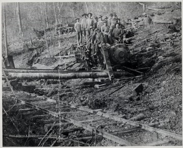 Crew members pose on top of a train wreckage.