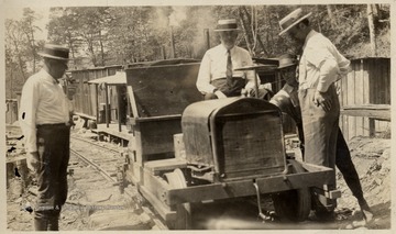 C.H. Holden, of Parkersburg, C.W. Sprinkle, of Cincinnati, and Dave Cougar, of Skelt, W.Va. checking a Model "T" converted for use on the Pickens and Webster Spring Railroad.