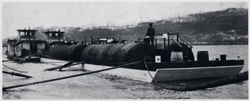 Barge carrying oil storage tanks.  Man standing in between the tanks.
