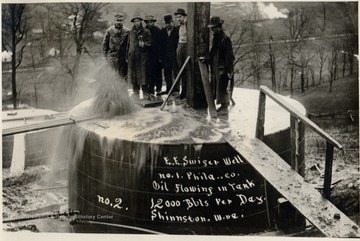 Six men standing on top of an oil tank.