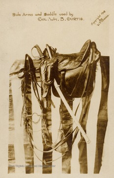 Side Arms and Saddle used by Colonel Wm. B. Curtis.  Items resting on an American Flag.  Copyright 1908 by W.T. Nicoll.