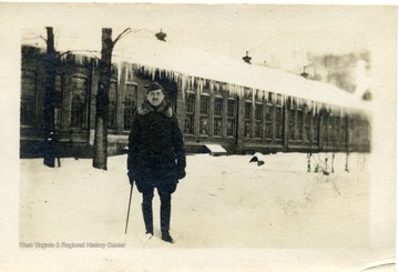 Candid portrait of Louis Bennett, Jr. standing in the snow in front of an icicle covered building.  This photograph was found in Bennett's Royal Air Force Wallet.