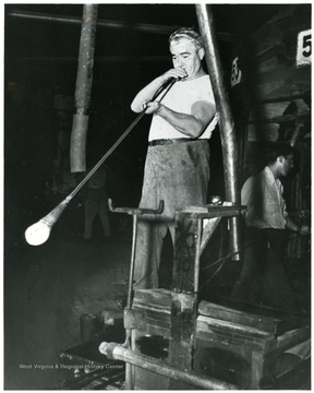 Man hand blowing glass at the Fostoria Glass Company, Moundsville, W. Va.