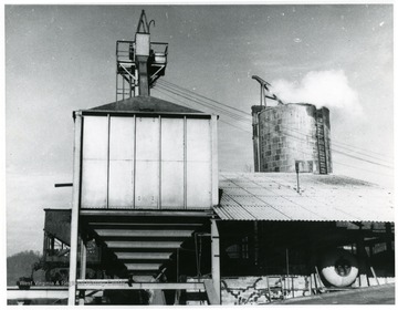 A smoke stack on the right billows steam or smoke, with a processing building in the center.