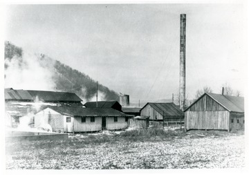 Factory buildings with a smokestack to the right.