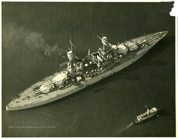 The U.S.S. West Virginia next to another much smaller boat. Stamped on back: Official photograph. Not to be used for publication by order of the Chief of the Bureau of Aeronautics.