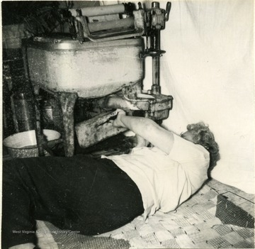 Mrs. W.D. Himes repairing a washing machine by replacing the belt. Photograph taken in Harrison County.