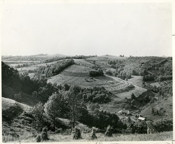 Scenic view of a farmhouse and the surrounding lands taken from the top of a mountain.  Photo courtesy Soil Conservation Service.