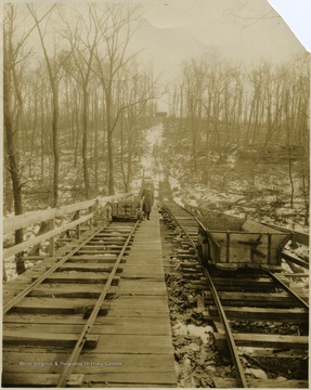 Unidentified man standing next to a coal car on tracks leading from a Monongalia County mine.