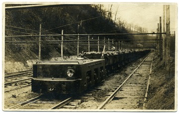 Postcard of an electric locomotive carrying coal and miners.
