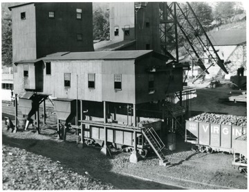 This picture shows a days run of coal below Summerlee Tipple just before being moved by the railroad crews. Three cars of stove size, four cars of lump, four cars of egg and eleven cars of slack constitute the loading for the day.<br />Note how the cars are trimmed! What a neat appearance they present! Even the cars of slack are evenly loaded and trimmed. Careful inspection and frequent supervision accounts for results like the camera shows. Every attention is paid to the preparation and marketing of 'White Oak' coal. No detail is to small to receive our most careful attention. Conditions shown here prevail at all the White Oak Mines. Each and every car leaving a White Oak Mine is carefully inspected as loaded by an experienced and competent inspector; all impurities removed and the car fully loaded and properly trimmed just as you see them in this picture. 