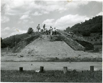 Several men digging on top of a mound.