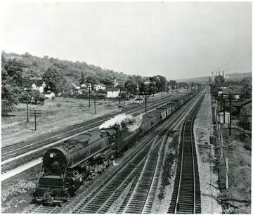 A New York Central System train moves along the track hauling many cars of coal.