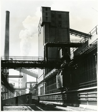 Caption on back reads 'Coke Ovens, Steam rises from the quenching tower of the new by-product coke battery at the Lorain, Ohio, works of U.S. Steel's National Tube Division. Coke production has been doubled with the instalation of three new batteries of 59 ovens each. Other improvements at Lorain include enlargment and installation of coal and coke handling facilities, numerous changes in the equipment for recovery of coal chemicals, and a coal and coke laboratory. Photo from U.S. Steel Corp., and copy negative September 1952.'