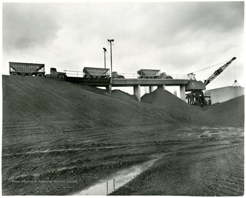 Consolidation Coal Company Trucks and a crane on a bridge over piles of coal.