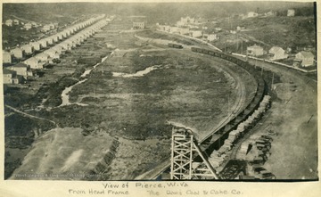 Aerial view of Pierce, W. Va. Davis Coal and Coke Company.  Part of headframe, miner's houses, railroad tracks, and coal cars visibile.