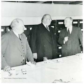Three coal officials talking behind a table during a Consolidation Coal Co. Inspection trip.