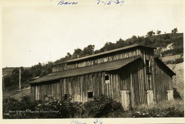 Wooden barn sitting along hillside.
