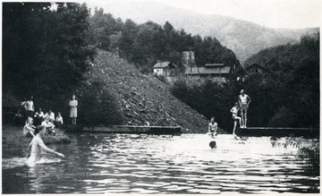 People swimming with coal buildings in the background.