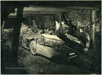 Miners and filled coal cars inside a mine.