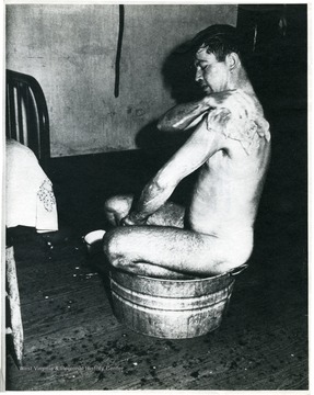 Miner washing himself in a small washtub.