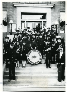 Group portrait of the New River Coal Company band in uniform standing on steps.