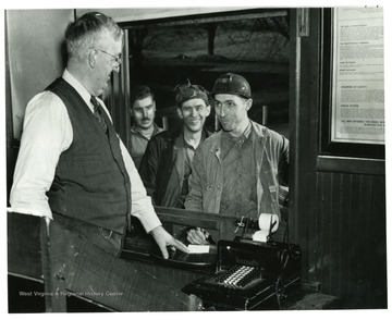 Miner receiving his payment from the office on payday.