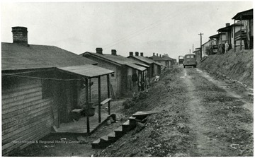 A road separates rows of company houses built into the hillside.