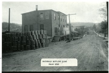 Side view of the bottling plant at MacDonald.  Barrels stacked beside the plant building.