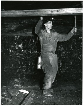 Miner putting bolts into the roof of a mine for support.