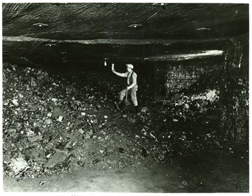 Miner checking for gas on pile of coal after it was shot down.