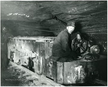 Two miners next to an electric locomotive.