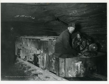 'An Electric Locomotive: Good dependable motive power is just as necessary in a coal mine as on a railroad. This picture shows on of White Oak's ten ton electric locomotives used to haul loads and distrubute empties in our mines. A crew consists of a motorman and brakeman, or trip rider, who pull loads from the working places to convenient sidings where they are picked up by main line locomotives, who haul to the tipple or shaft bottom. A large producing mine uses fifteen and twenty locomotives and five hundred mine cars in maintaining production.'
